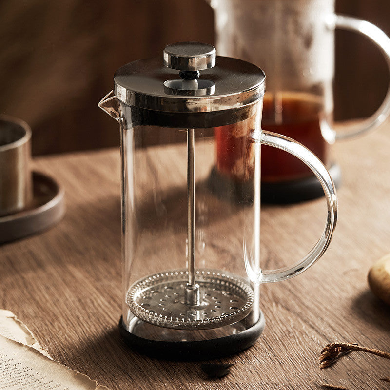 Glass French press with steel lid on a wooden table