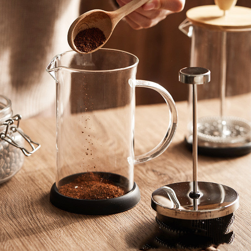 Ground coffee spooned into the glass jug of the French press